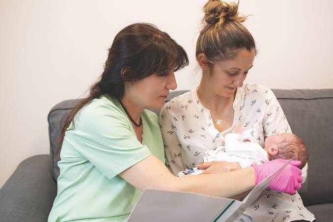 A doula sitting with a mother and her newborn, offering support