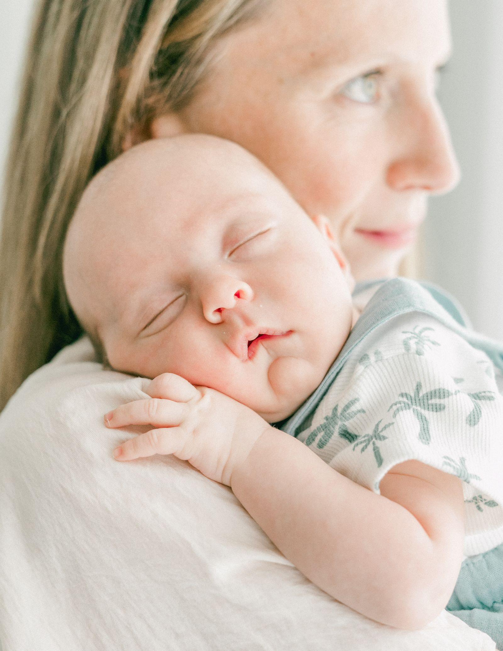 A caregiver gently soothing a sleeping newborn