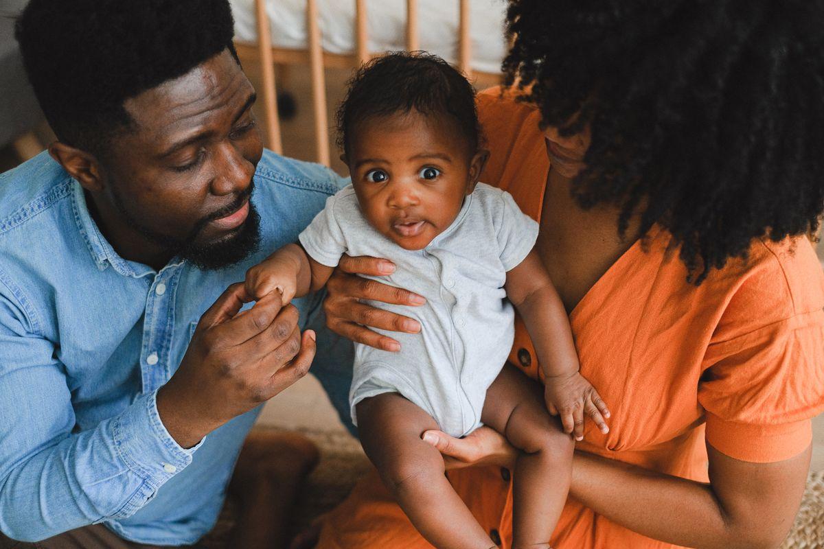Two parents at home cradling their baby together